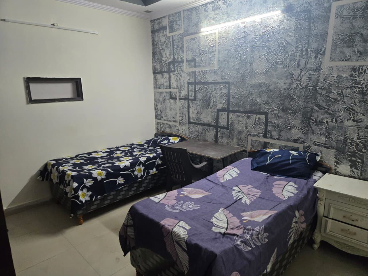 Furnished double-sharing room at Manvi Home Stay PG with beds, side tables and study space